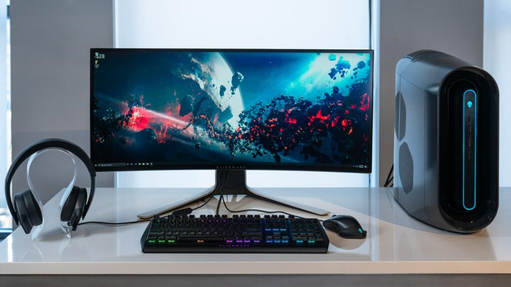 A widescreen Alienware monitor on a desk next to a PC and headphone setup. Could this be the Best Monitor For Work?