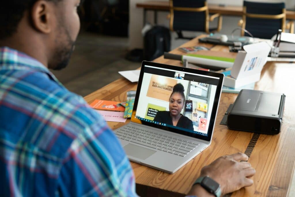 A person in a blue shirt talks to someone on a laptop while learning how to pitch to clients.