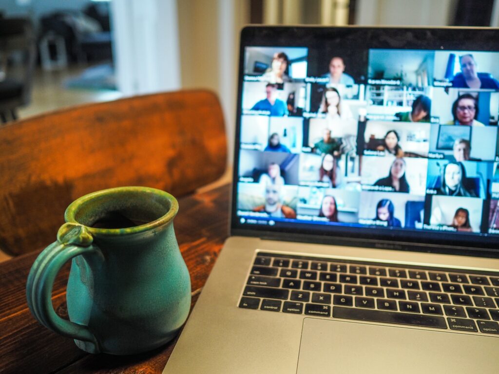 A laptop computer is on a desk with a mug next to it, on the screen is a Zoom call which you could easily record video conference with XSplit Broadcaster.