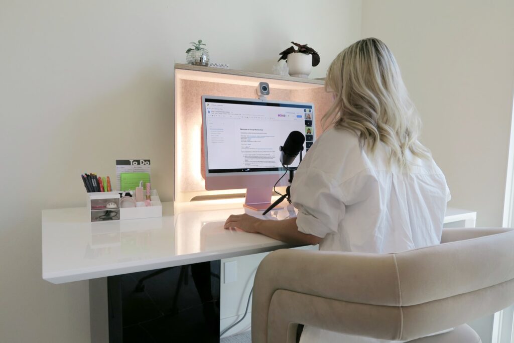 A person sat in front of a computer with a webcam on it on their desk using the best work from home microphone.